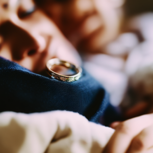 An image depicting a couple nestled together on a cozy couch, their intertwined fingers showcasing wedding rings